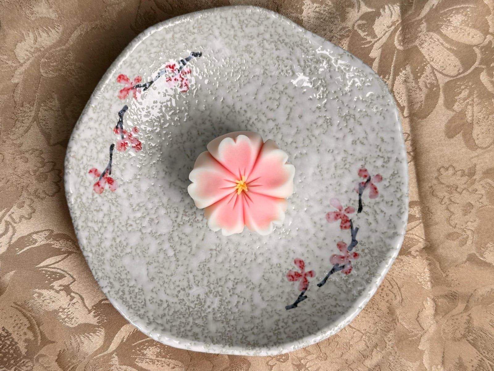 Pink cherry-blossom-shaped nerikiri on a hand-painted plate